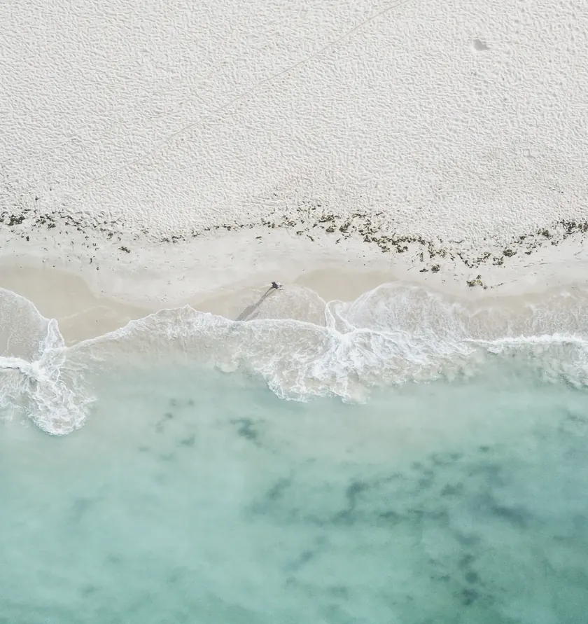Aerial view of a shoreline, white sand meeting turquoise water