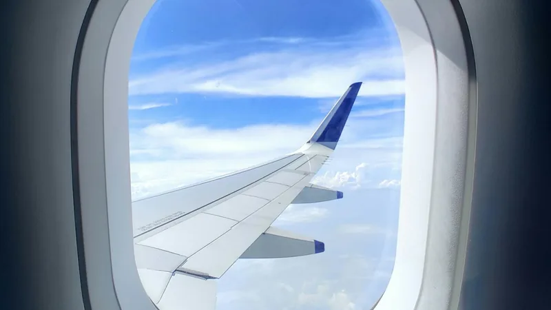 An aircraft wing seen through a cabin window above the clouds, flight-deal banner shown to frequent-flyer subscribers
